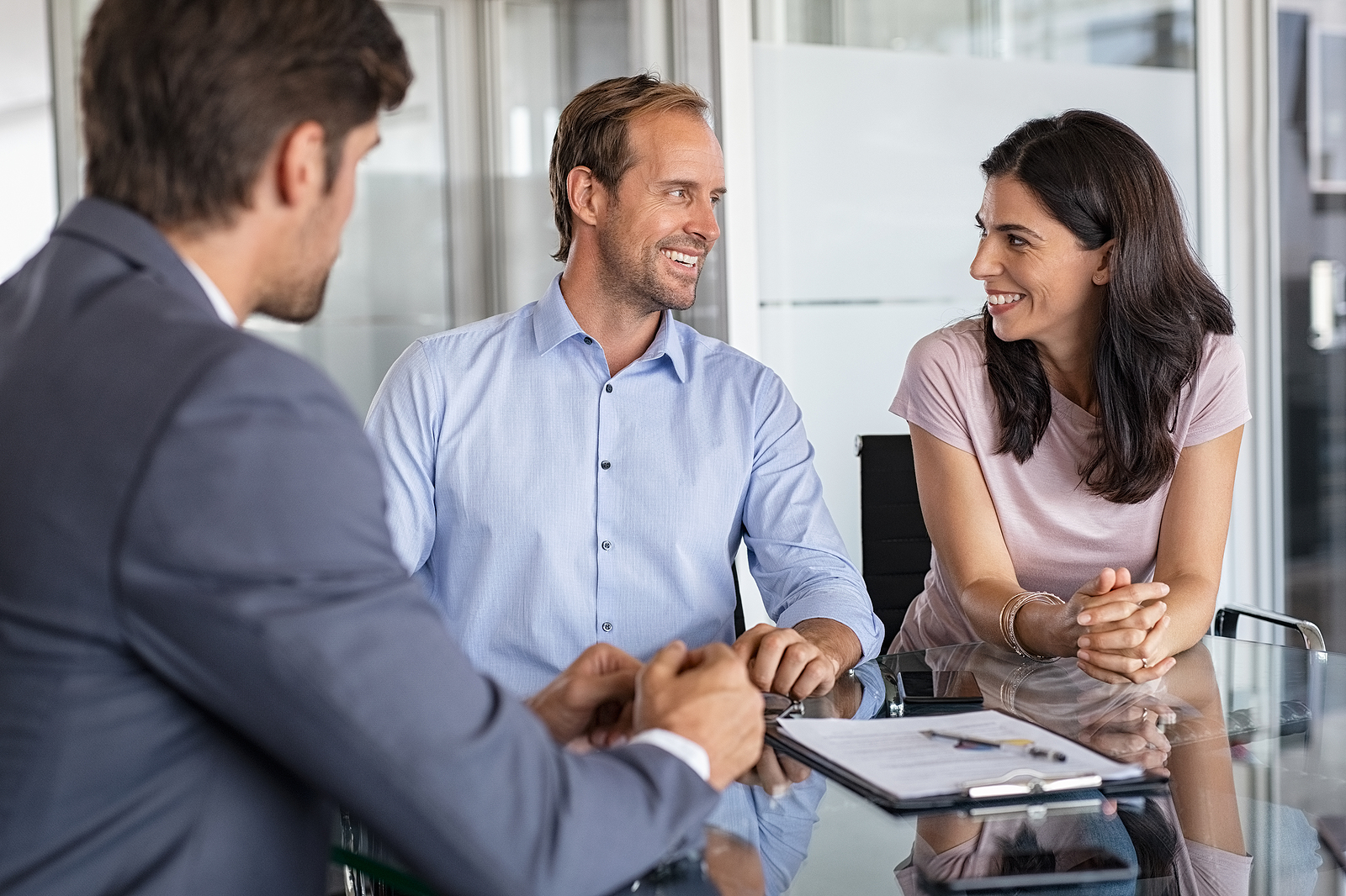 Mature smiling couple meeting financial advisor for investment at office. Financial consultant presents bank investments to man and happy woman. Middle aged couple consulting their bank agent. Saving
