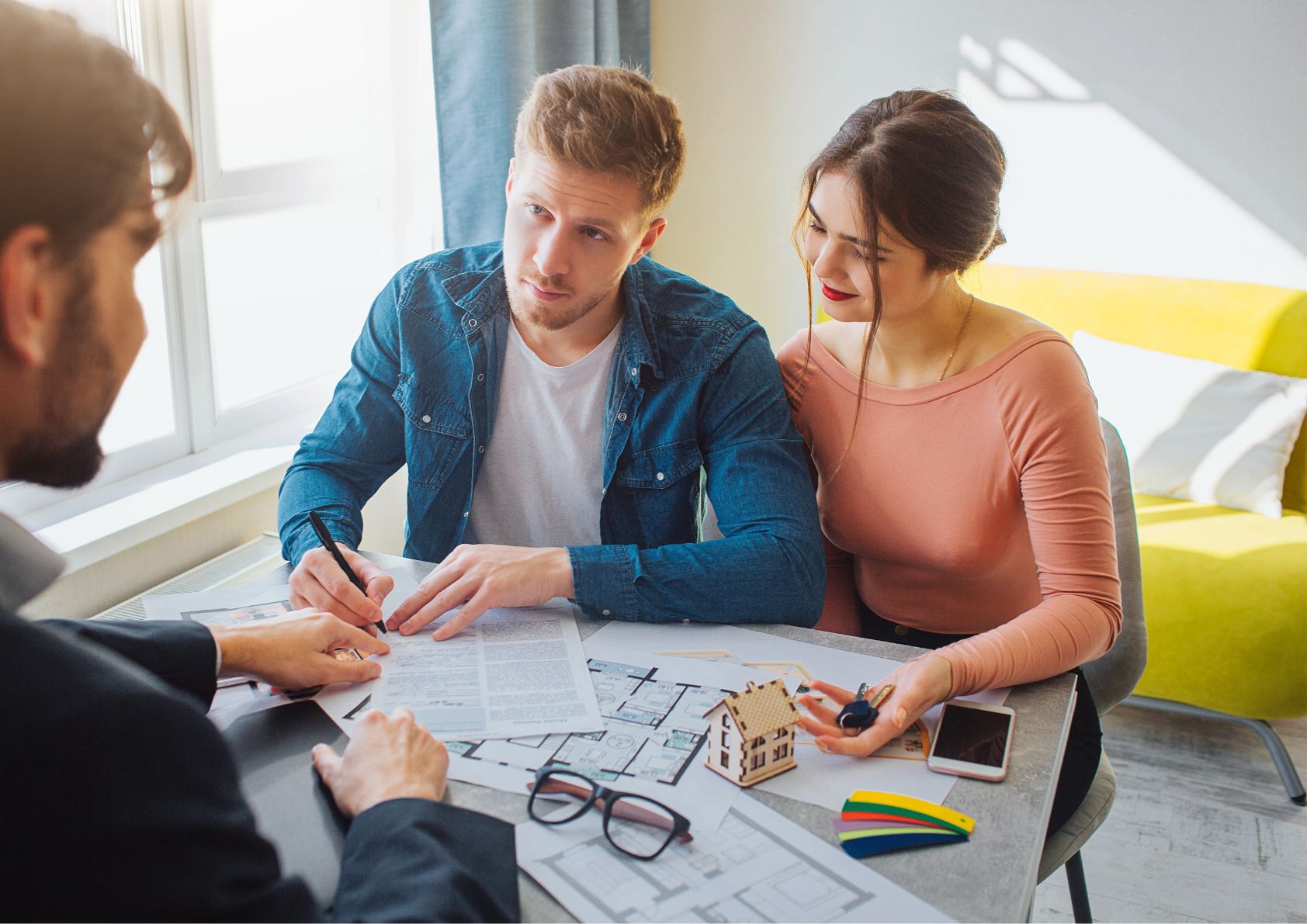 Young couple buying a home. Working with a Real estate professional on closing day. 