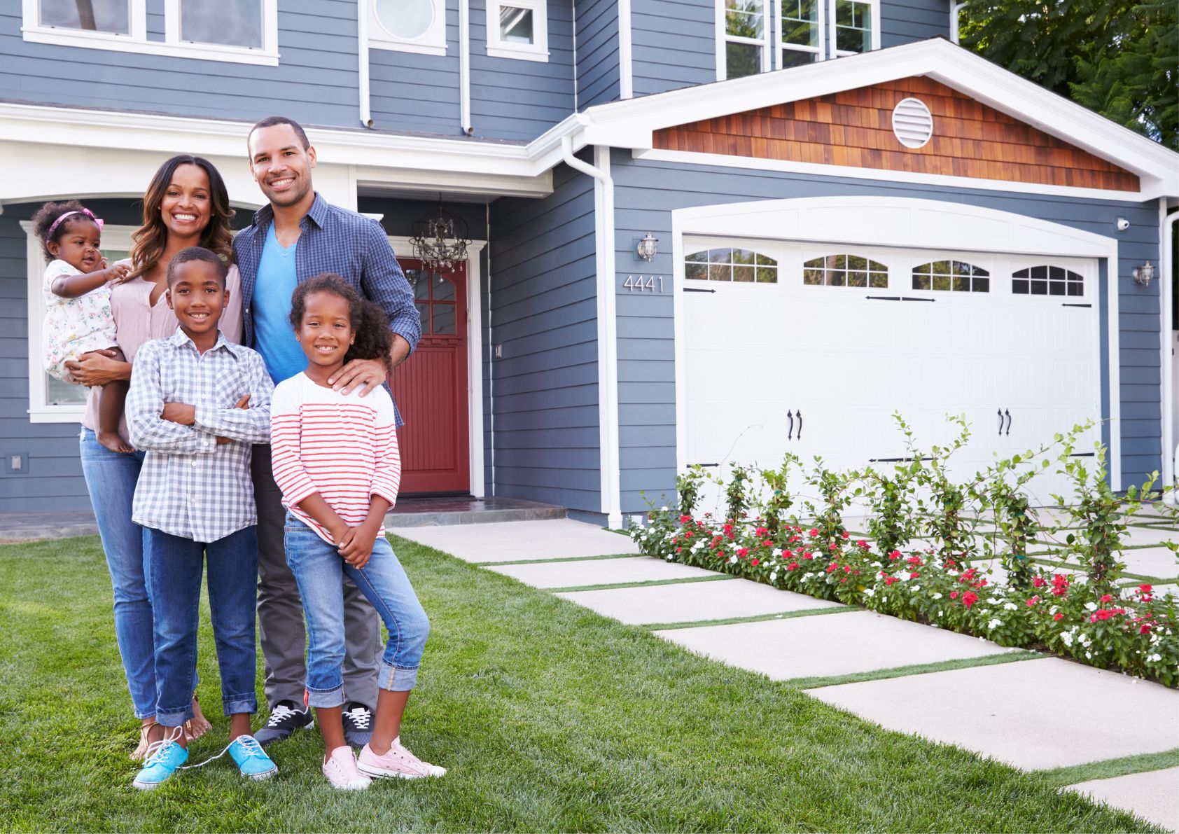 Happy family standing in front of a brand new home they bought and fixed up. 