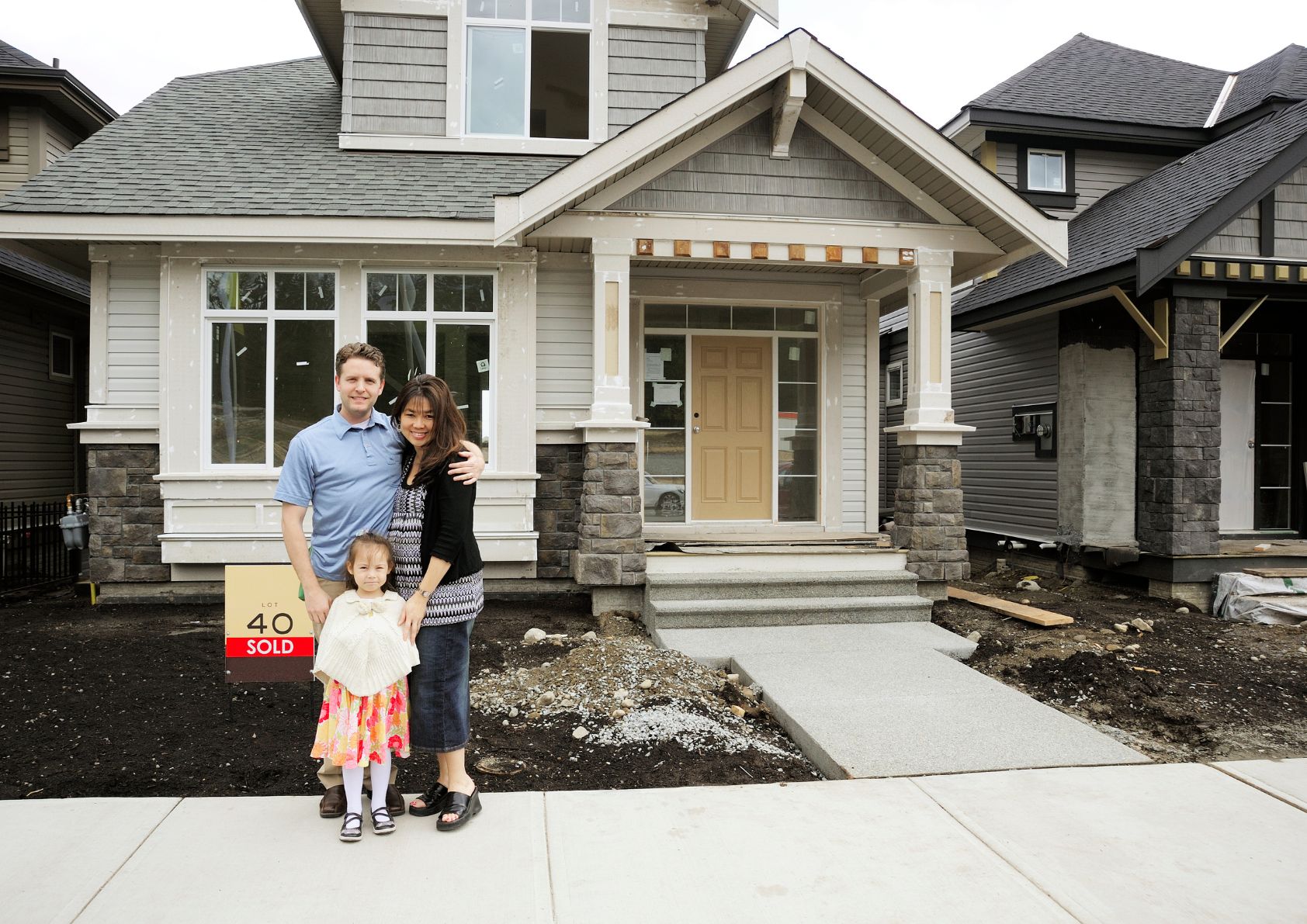 Happy family standing in front of a home they just bought. 