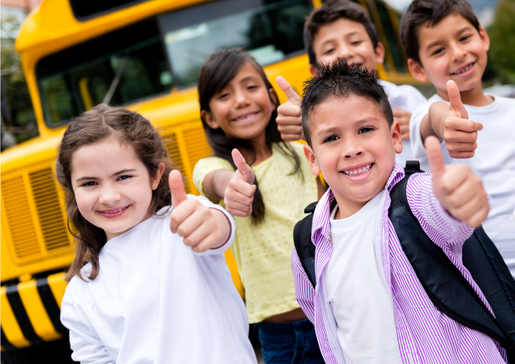 kids standing in front school bus giving thumbs up. 